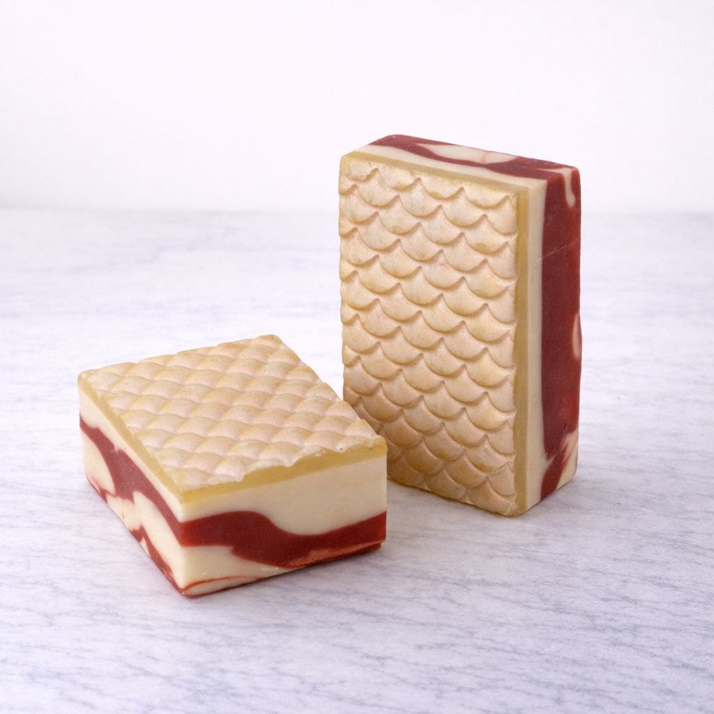 Two white mermaid-scale patterned soap bars on a white background