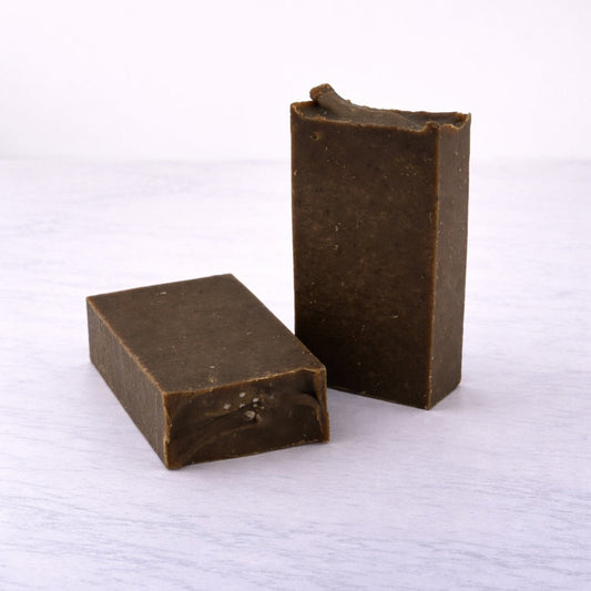 Two rectangular brown bars of soap on a white textured surface