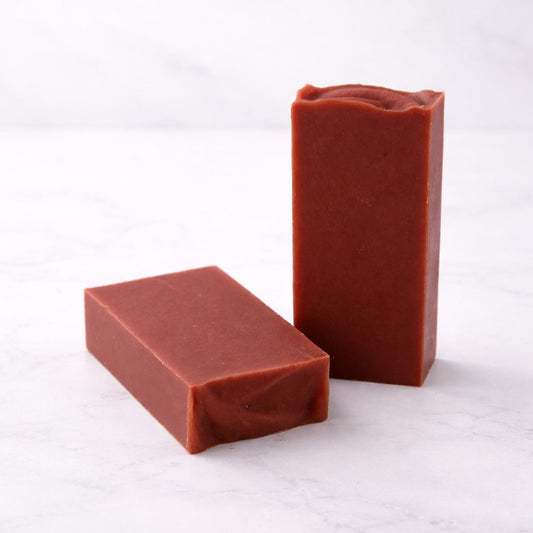 Two bars of red soap on a white marble surface
