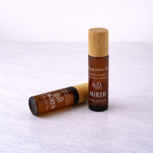 Two bottles of 'Mirth' fragrance oil on a white textured surface